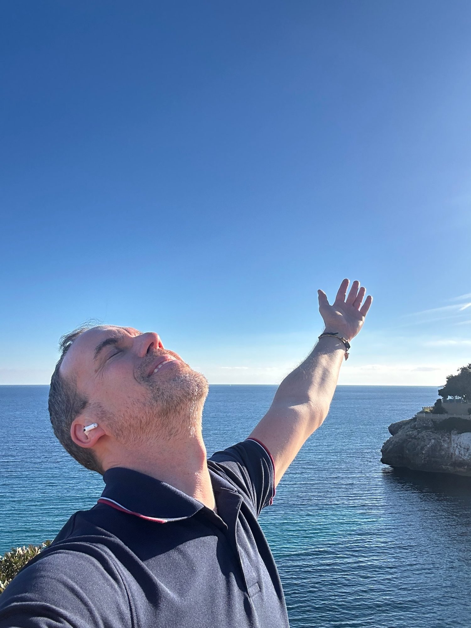 Manuel Bernardy by the sea, arm raised toward the sky